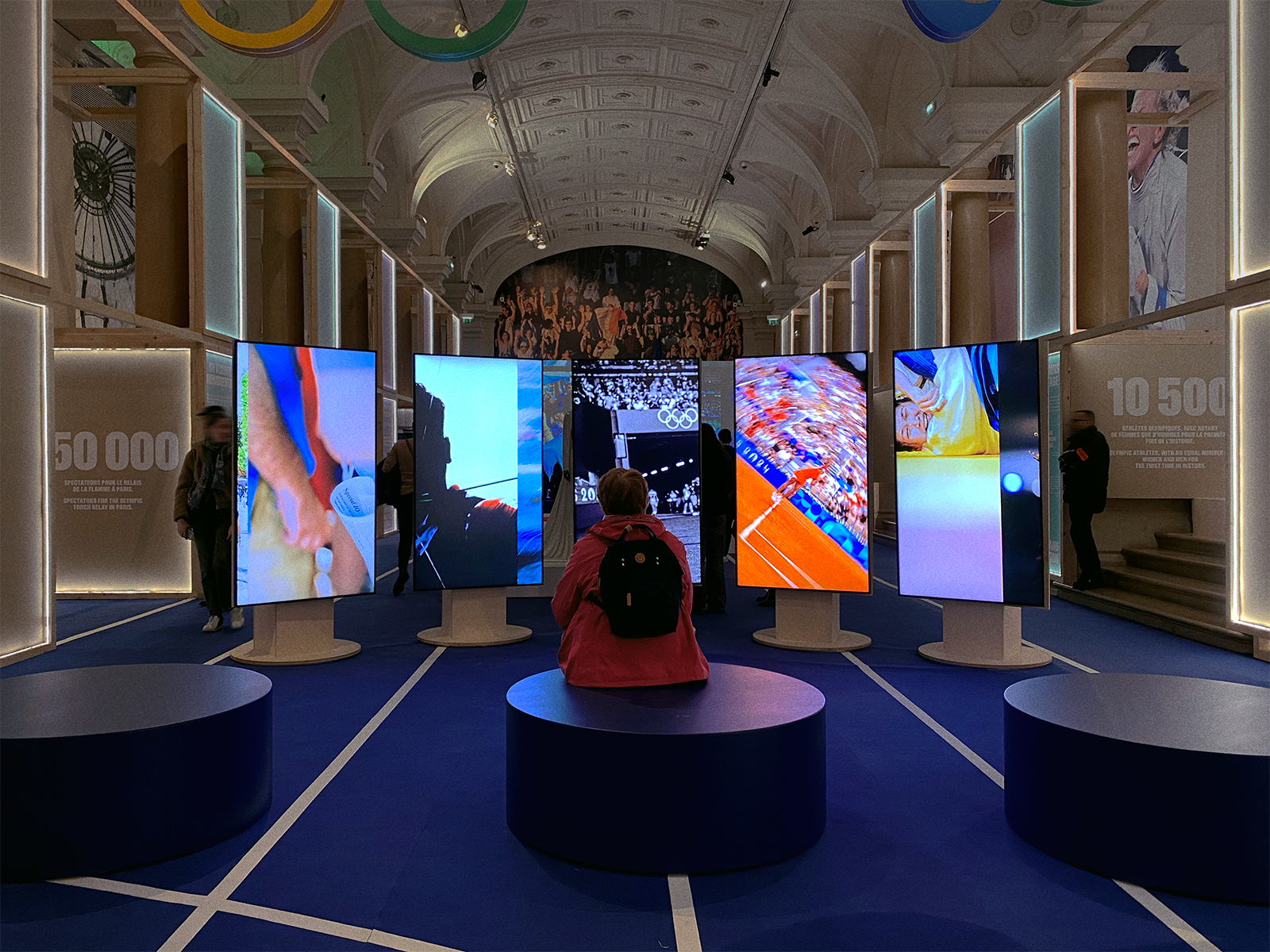 Vue de la projection des cinq portfolio de photographe sur des écrans verticaux dans l'espace de l'exposition