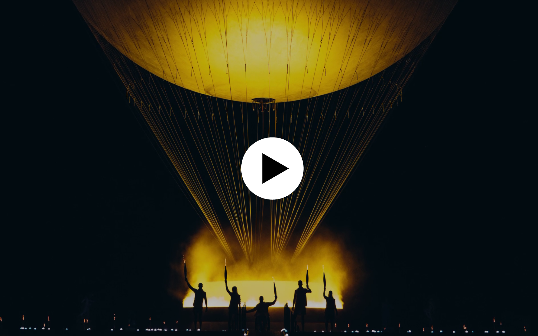 Image de la vasque olympique. Icône play en surimpression indiquant que l'image est cliquable et mène vers un contenu vidéo.