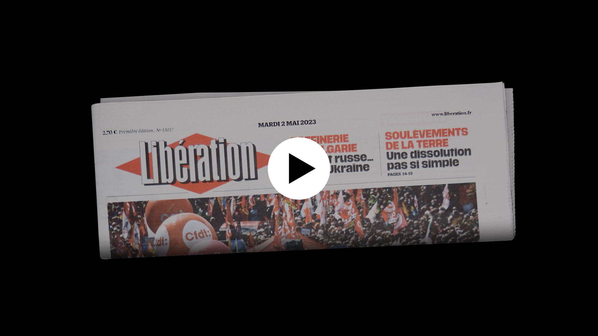 Image d'un exemplaire de Libération plié, on distingue le haut de la une avec le logo. Icône play en surimpression indiquant que l'image est cliquable et mène vers un contenu vidéo.